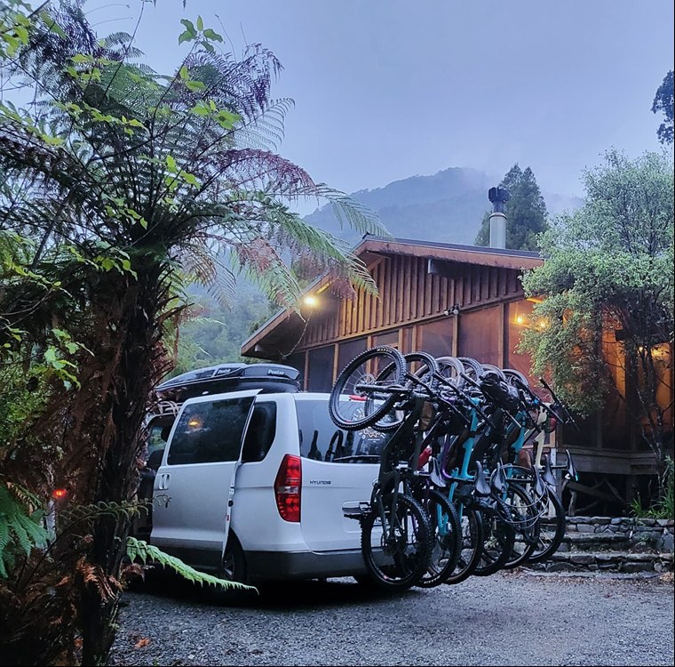Shuttle van carrying multiple mountain bikes on its rear rack